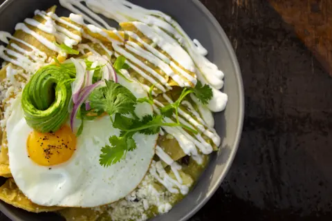 Chilaquiles verdes with a fried egg and an avocado rose