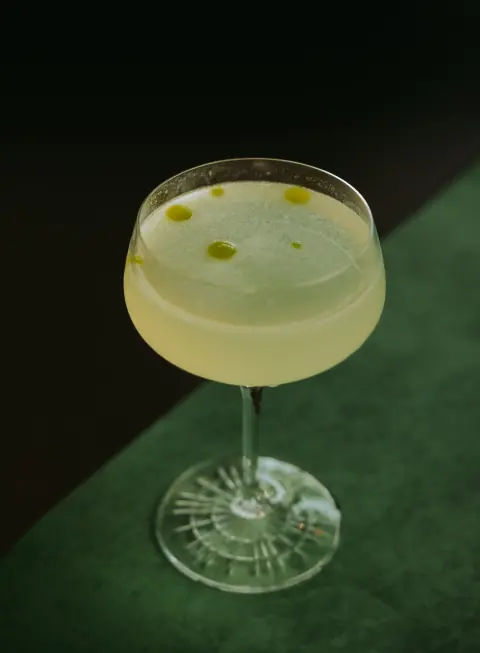 A pale green cocktail in a coupe