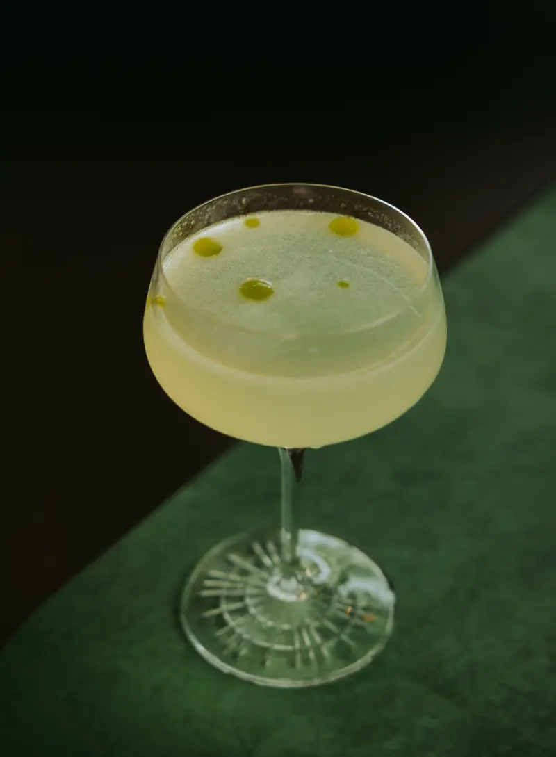 A pale green cocktail in a coupe