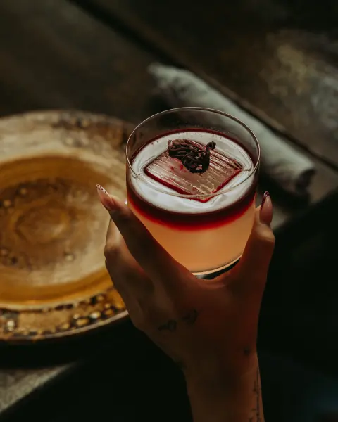 A red cocktail in hand
