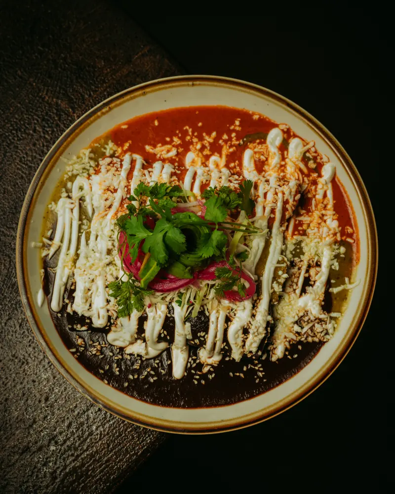 Enchiladas topped with crema and pickled onion